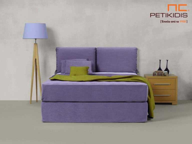 Υφασμάτινο κρεβάτι Joys της Linea Strom σε μοβ ύφασμα μονόχρωμο και λεπτομέρεια δεσίματος στις μαξιλάρες του κεφαλαριού. Το ύφασμα είναι αποσπώμενο και από τη βάση και από το κεφαλάρι για εύκολο καθάρισμα.