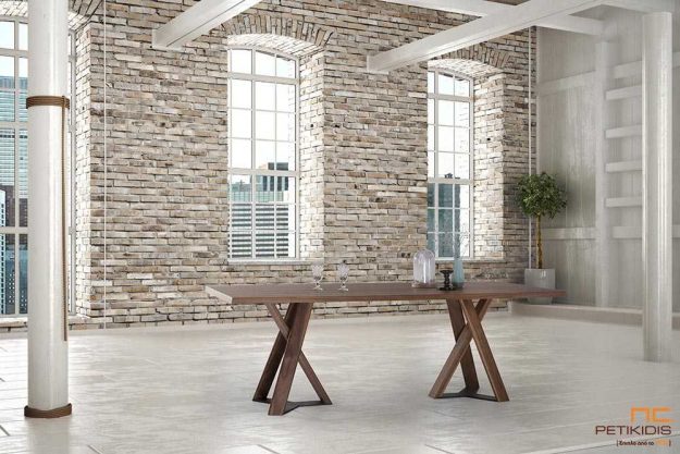 Τραπέζι Dune από ξύλο καρυδιάς με δύο κεντρικά πόδια από μασίφ καρυδιά με λεπτομέρεια μετάλλου στη βάση. Διαθέτει δυνατότητα προέκτασης.